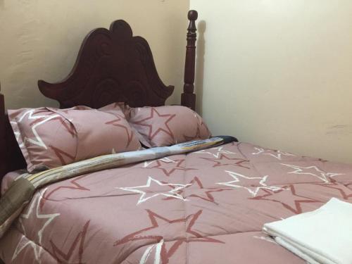 a bed with a pink comforter with stars on it at Mary Apartments in Mbale