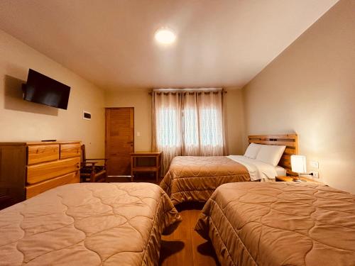 a hotel room with two beds and a television at Alpamayo Casa Hotel - Restaurante in Yungay