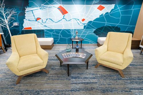 two chairs and a coffee table in a room with a map at Holiday Inn Express Hotel & Suites Kodak East-Sevierville by IHG in Kodak