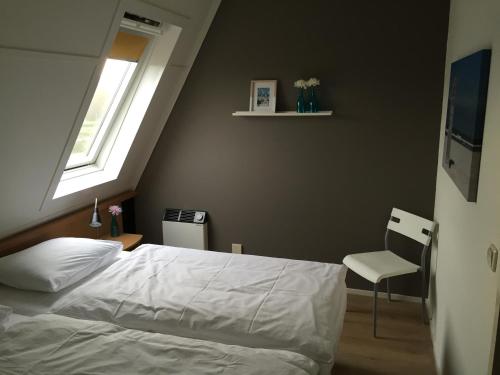 Un dormitorio con una cama y una ventana y una silla. en Appartement Anker, en Hollum