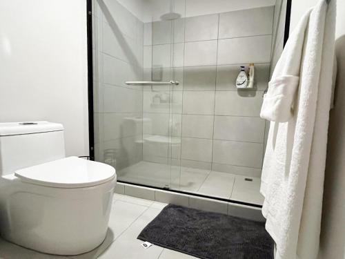 a white bathroom with a shower and a toilet at Serenity at 12, City Views and Wonderland Vibes! in Hatillo