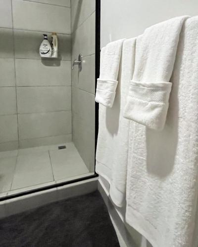 a bathroom with white towels hanging in a shower at Serenity at 12, City Views and Wonderland Vibes! in Hatillo