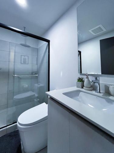 a white bathroom with a toilet and a sink at Serenity at 12, City Views and Wonderland Vibes! in Hatillo