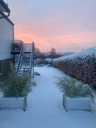 a snow covered walkway leading to a house with a staircase at Terrier Ovifat - logement familial Nature et Sauna in Ovifat