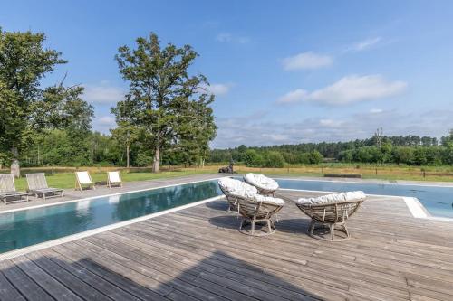 une terrasse avec des chaises et une piscine dans l'établissement Villa avec piscine en forêt, 2H Paris,, à Neuvy-sur-Barangeon