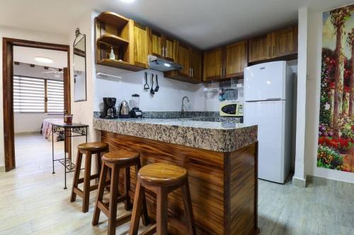 a kitchen with a bar with stools and a refrigerator at Departamento cerca a la Playa in Puerto Vallarta