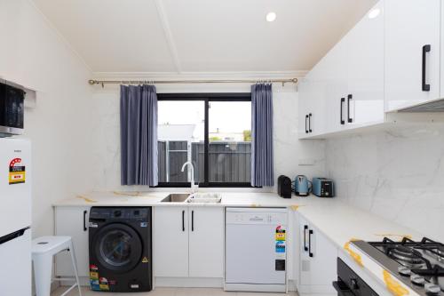a kitchen with a washing machine and a sink at Glenelg Modern Studio, QBed,Wifi in Glenelg