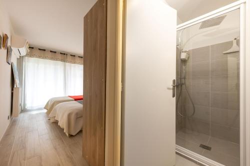 une salle de bain avec douche et une chambre avec un lit dans l'établissement Tanit charmant 3 pièces, grande terrasse, à Antibes