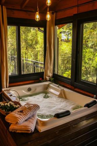a bath tub in a room with two windows at Chalé Riozinho in Alfredo Wagner