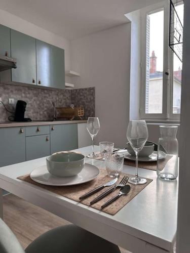 - une cuisine avec une table, un bol et des verres à vin dans l'établissement Appartement les Lilas, à Dijon