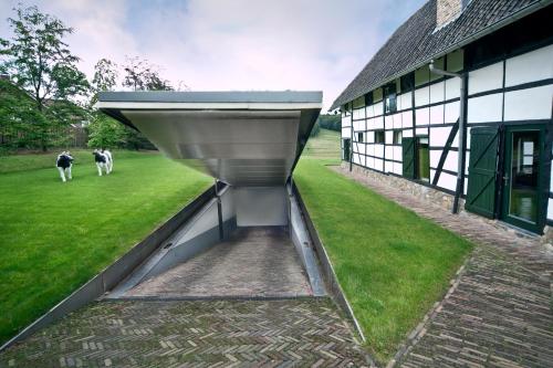 a barn with cows walking in the grass next to a building at Auberge de Smockelaer in Heijenrath