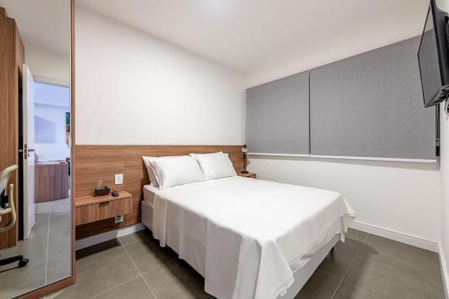 a bedroom with a white bed and a television at GO Rio Branco by LikeHome in Porto Alegre