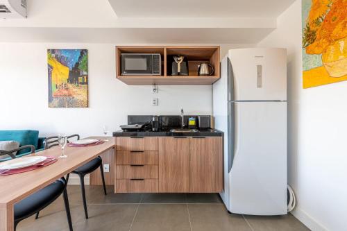 a kitchen with a white refrigerator and a table at GO Rio Branco by LikeHome in Porto Alegre