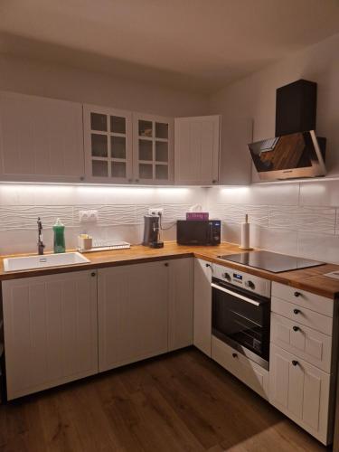 une cuisine avec des armoires blanches, un évier et une cuisinière dans l'établissement Appartement in Sannois - 100m from train station and 20 min from Paris St Lazare, private parking, à Sannois