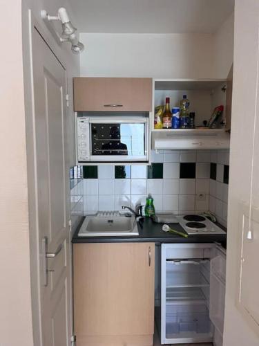 une petite cuisine avec un évier et un micro-ondes dans l'établissement Manon, 2 pièces, Wifi, coeur historique, calme, central, à La Rochelle