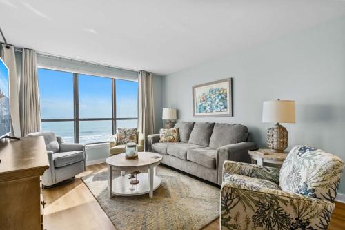 a living room with a couch and chairs and a large window at Windemere Beachfront Oasis with Hot Tub and Pool Access in Myrtle Beach