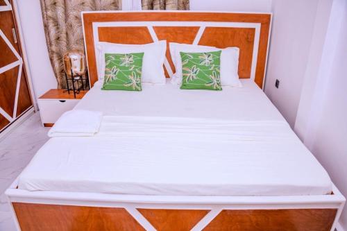 a bedroom with a white bed with green pillows at Appartement Meublé Haut de Gamme in Brazzaville