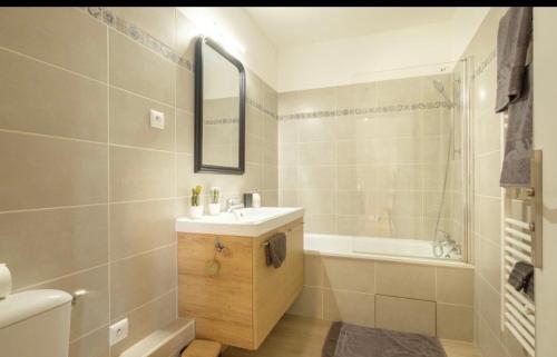 une salle de bain avec un lavabo, une baignoire et un miroir dans l'établissement Duplex Disney, à Chessy