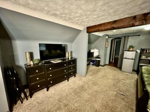 a living room with a flat screen tv and a dresser at Schillhaus Lvl 3 in Louisville