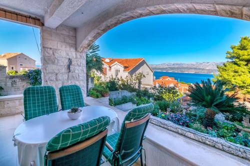 een balkon met een tafel en stoelen en uitzicht op het water bij Apartments Paco in Postira
