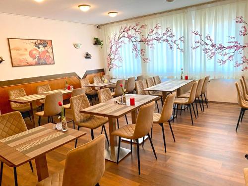 a restaurant with wooden tables and chairs and windows at Hotel Wesselényi in Győr