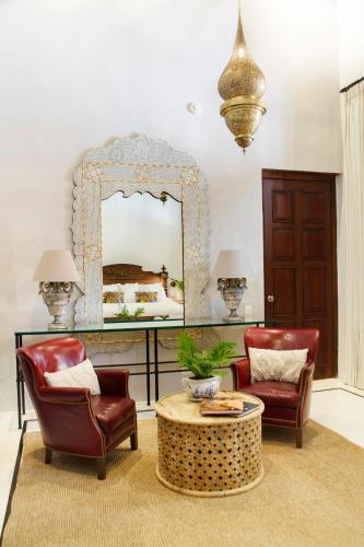 a living room with two chairs and a table and a mirror at Casa de la Renta By Mustique in Cartagena de Indias