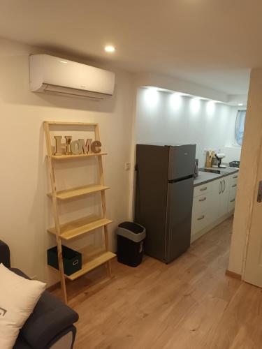 Elle comprend une petite cuisine équipée d'un réfrigérateur noir et d'une étagère. dans l'établissement Appartement cosy, à Salindres
