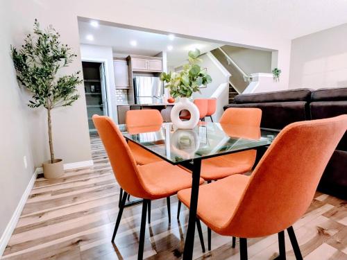 a dining room with a glass table and orange chairs at A Slice Of Heaven In Airdrie By Eagleswingshomes1 in Airdrie