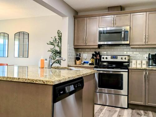 a kitchen with stainless steel appliances and wooden cabinets at A Slice Of Heaven In Airdrie By Eagleswingshomes1 in Airdrie