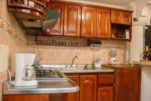 a kitchen with wooden cabinets and a sink and a blender at Amplia Casa a 10 min de la Basílica - Chiquinquirá in Chiquinquirá