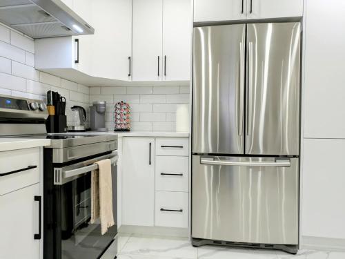 a stainless steel refrigerator in a kitchen with white cabinets at A Slice Of Heaven In Chestermere in Calgary
