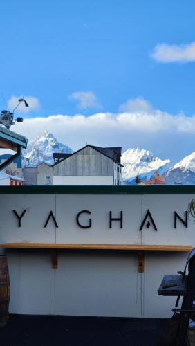 a sign on a building with mountains in the background at YAGHAN HOSTEL in Ushuaia