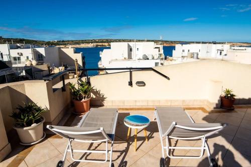 a patio with chairs and a table on a balcony at Aloe Vera penthouse corner in Is-Sellum