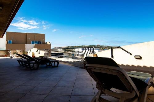 a patio with chairs and tables on a building at Aloe Vera penthouse corner in Is-Sellum