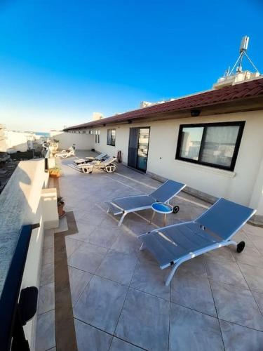 a patio with two lounge chairs and a building at Aloe Vera penthouse corner in Is-Sellum