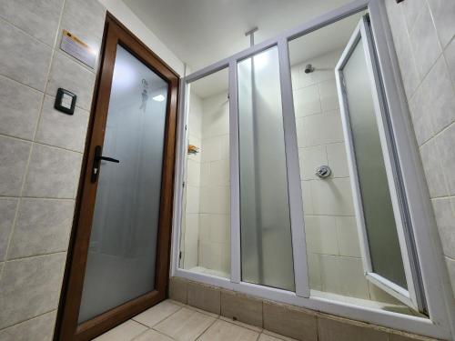 a bathroom with a shower and a glass door at YAGHAN HOSTEL in Ushuaia