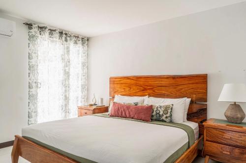 a bedroom with a bed with a wooden headboard and a window at Casa Tranquila - Ciudad del Mar 90 in Jacó