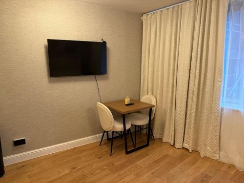 a dining room table with chairs and a television on the wall at Central London Studio Apartment in London