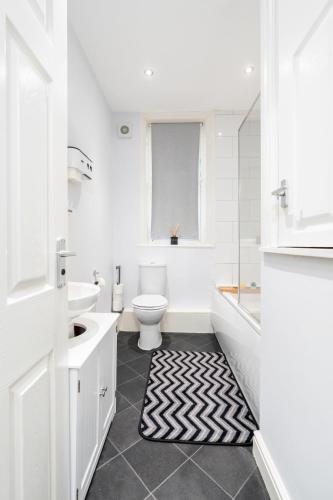 a white bathroom with a toilet and a tub and a sink at Stunning Doncaster City Centre Apartment, with 2 Double beds in Doncaster