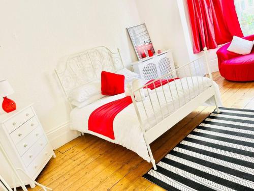 a white bed in a room with a red chair at Taswell Road in Portsmouth