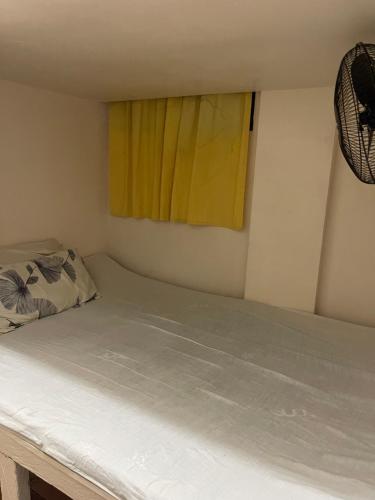 a bed in a room with a yellow window at Maria Kulafu Lodging House Pier site- Santa Clara office 2nd Floor in Cagba