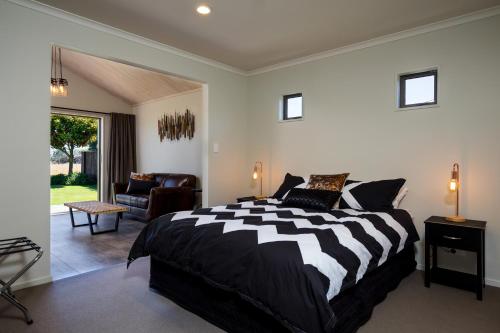 a bedroom with a black and white bed and a living room at 26 On Clearwater in Blenheim