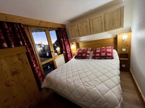 une chambre avec un lit avec des oreillers rouges et une fenêtre dans l'établissement Résidence Nereides - 3 Pièces pour 7 Personnes 67, à Mâcot La Plagne