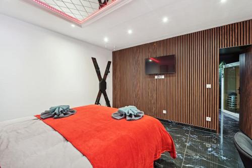 a bedroom with a red bed with a tv on a wall at Love Room - Suite avec jacuzzi et sauna privatif in Corbeil-Essonnes