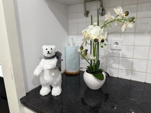 a white teddy bear sitting on a counter with a vase of flowers at Francisca River House in Vila Nova de Gaia