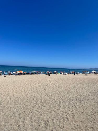 a group of people on a beach with umbrellas at Appartement pied sur mer in Fnidek