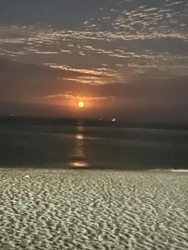 a sunset on a beach with the sun in the distance at Appartement pied sur mer in Fnidek