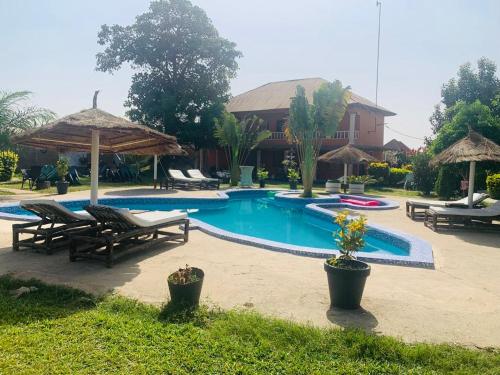 a swimming pool with chairs and umbrellas in front of a house at Alhasia Ecoville Jambur Gambia in Jambur