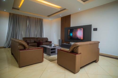 a living room with two chairs and a flat screen tv at Edmur GRA in Lagos