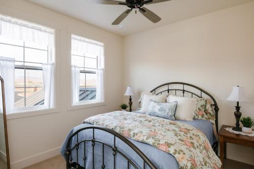 a bedroom with a bed with a fan and windows at Hidden Springs RV Resort in Ivins